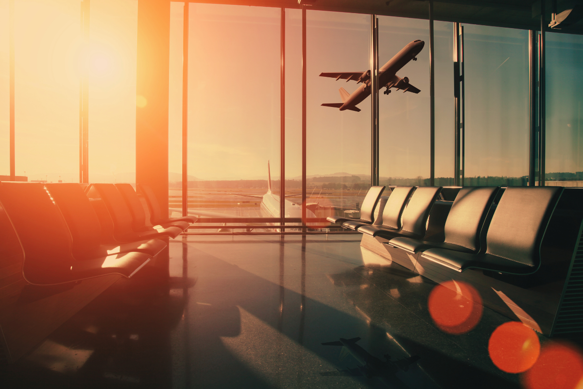 Image inside an airport with plane taking off in the background
